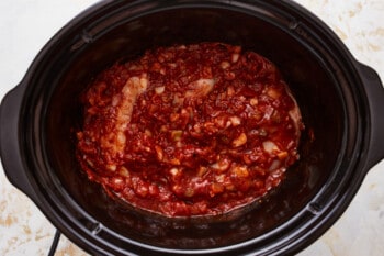 A crock pot filled with meat and sauce.