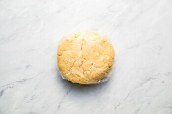 A loaf of bread wrapped in plastic on a marble surface.