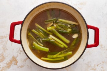 A pot of soup with green onions in it.