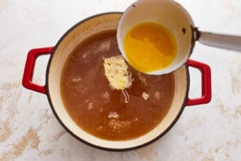An egg being poured into a pot of soup.