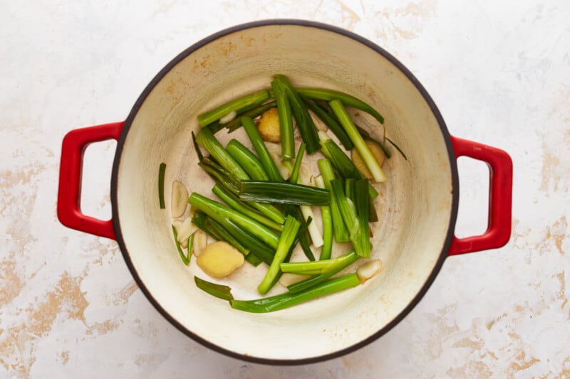 A pot with green onions and potatoes in it.