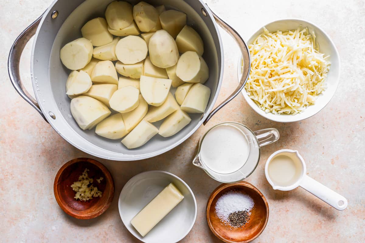 A pot with potatoes, cheese and other ingredients on a table.