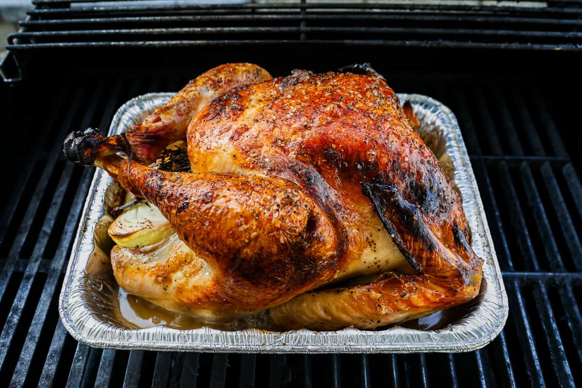 A roasted turkey sitting on a grill.
