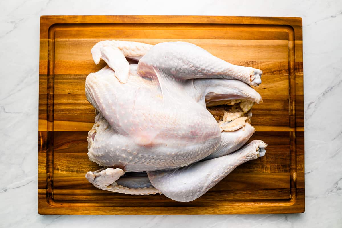 A white turkey on a wooden cutting board.