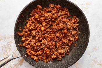 A frying pan with ground beef in it.