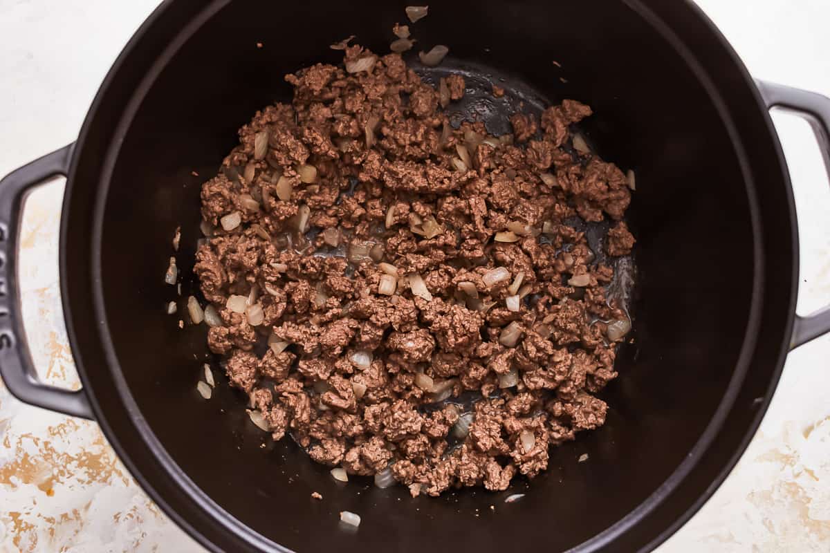 A black pot filled with ground beef and onions.