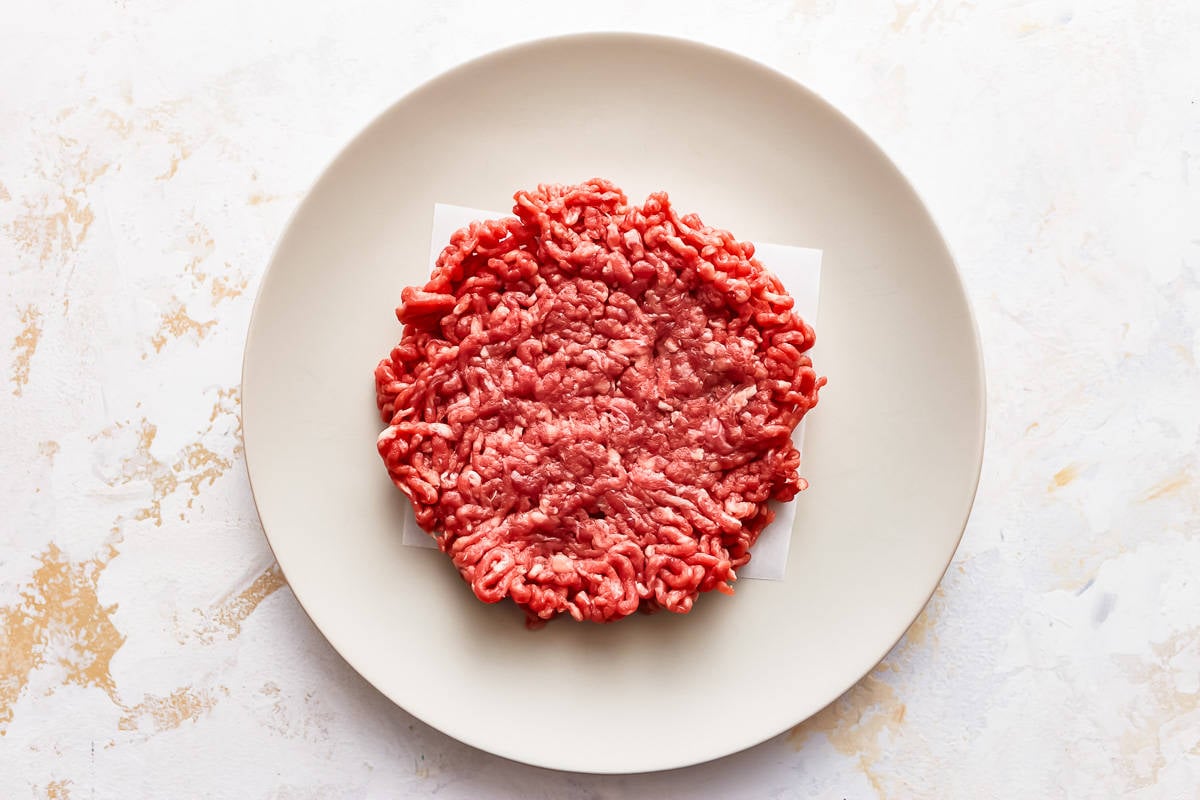 Ground beef burger patty on a plate.