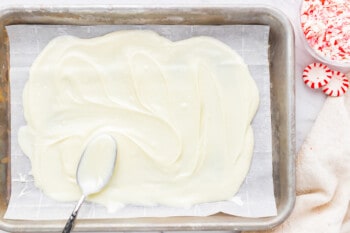 White icing on a baking sheet with candy canes.