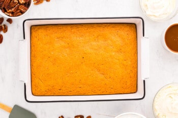 A white baking dish with a pumpkin cake in it.