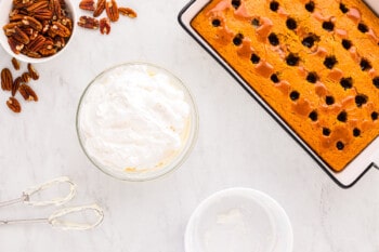 A cake with whipped cream and pecans on a table.