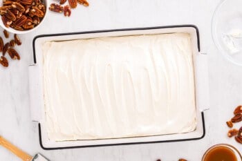 A white cake with pecans and icing in a pan.