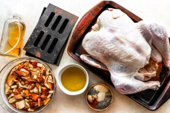 A turkey is sitting on a baking sheet with other ingredients.