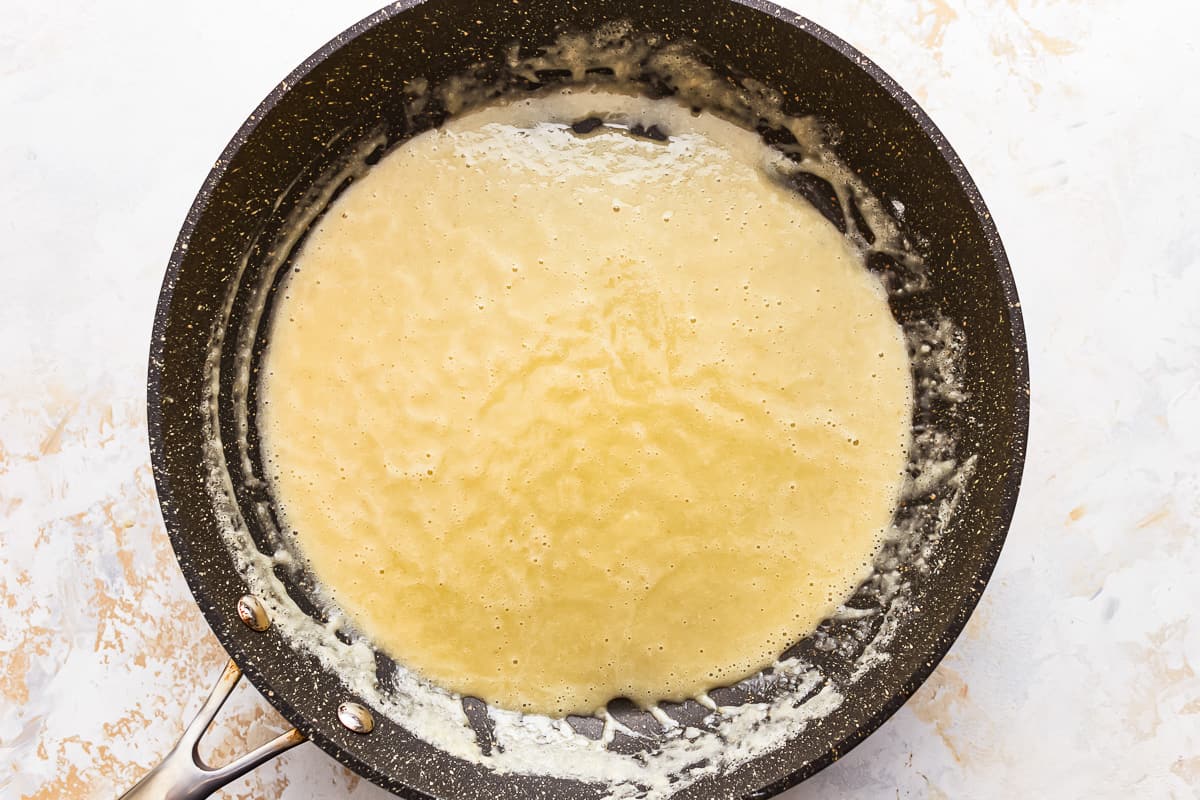 A frying pan with batter and flour in it.