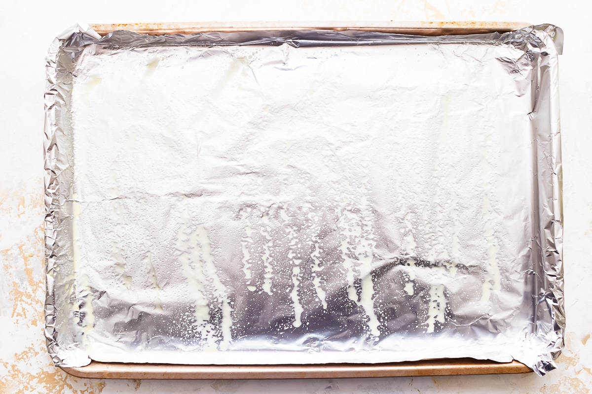 A baking sheet covered with aluminum foil that's been sprayed with non-stick spray.