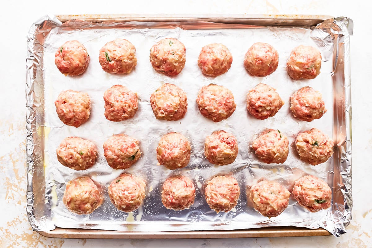 Raw meatballs on a baking sheet.