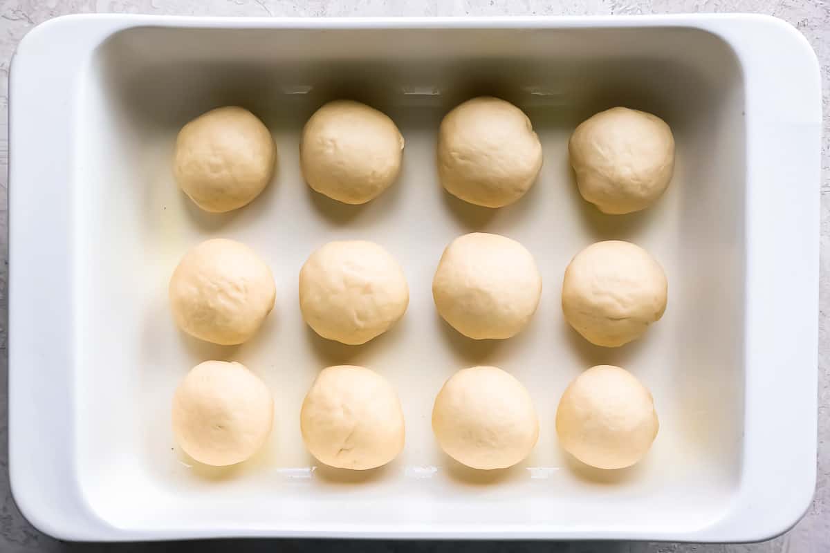 A white baking dish filled with dough balls.