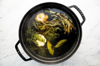 A pot with herbs and vegetables in it.