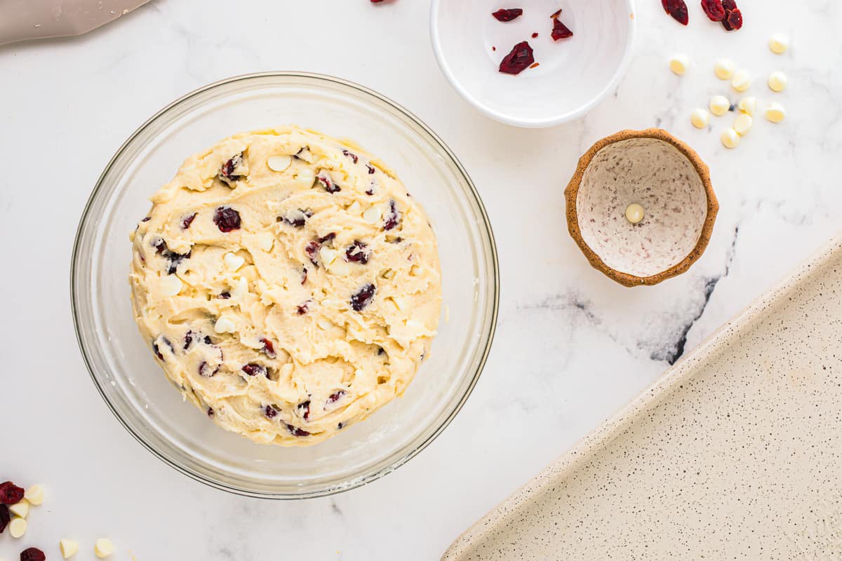 cookie dough with cranberries and white chocolate chips in a glass bowl.