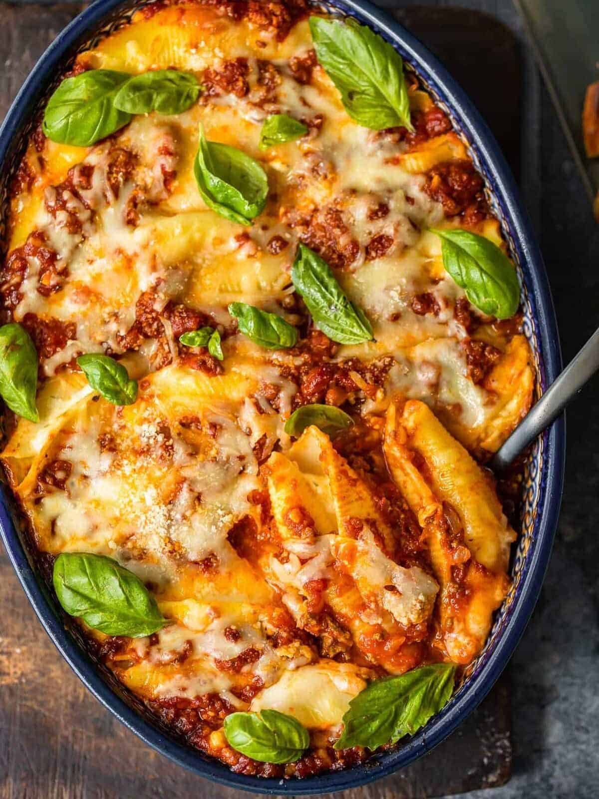 stuffed pasta shells in a casserole dish with a serving spoon