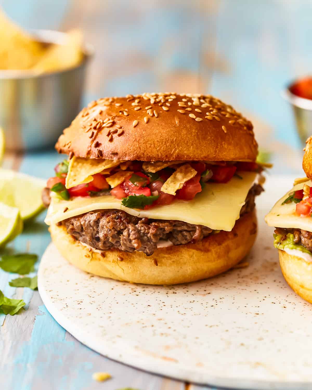 Taco burger on a plate with chips and salsa.