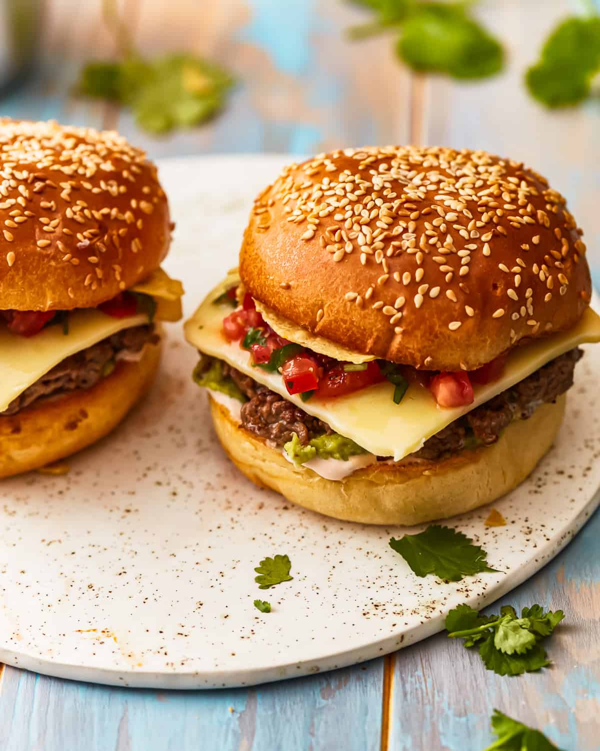 Close up on taco burgers, topped with salsa and guacamole.