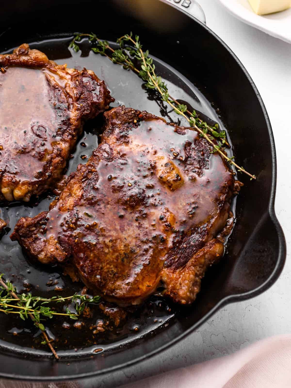 oven cooked steaks in a cast iron pan with thyme.