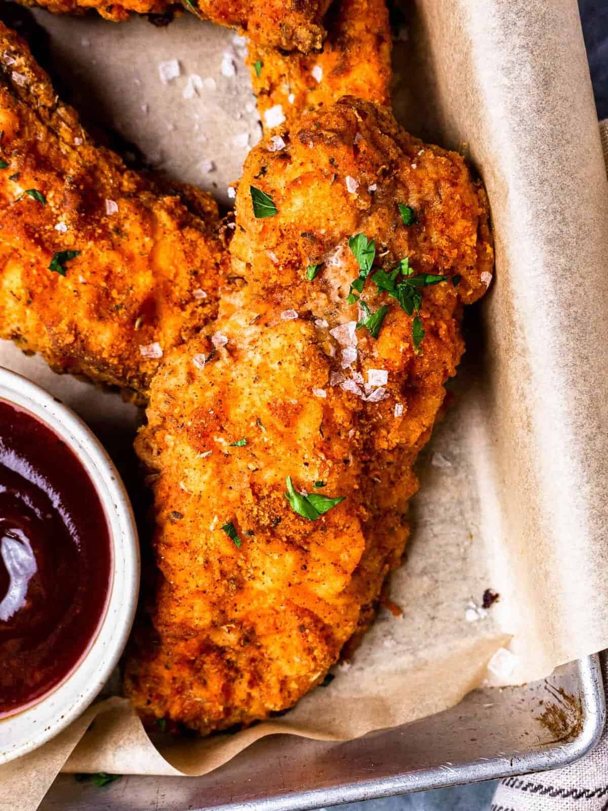 pieces of oven fried chicken on a tray with dipping sauces