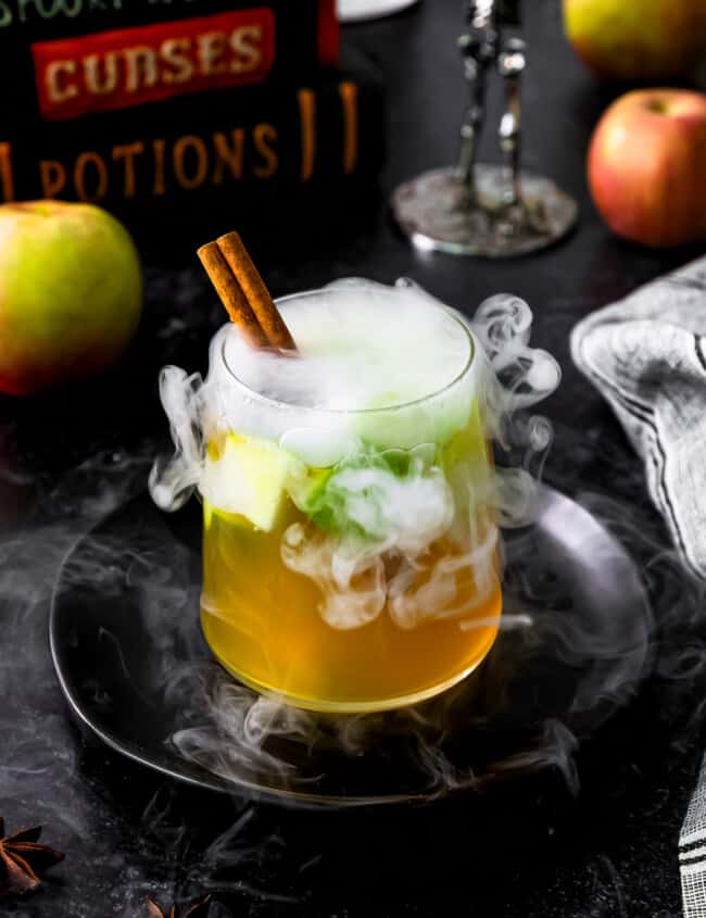 A witch's brew with apples and spices in a glass.