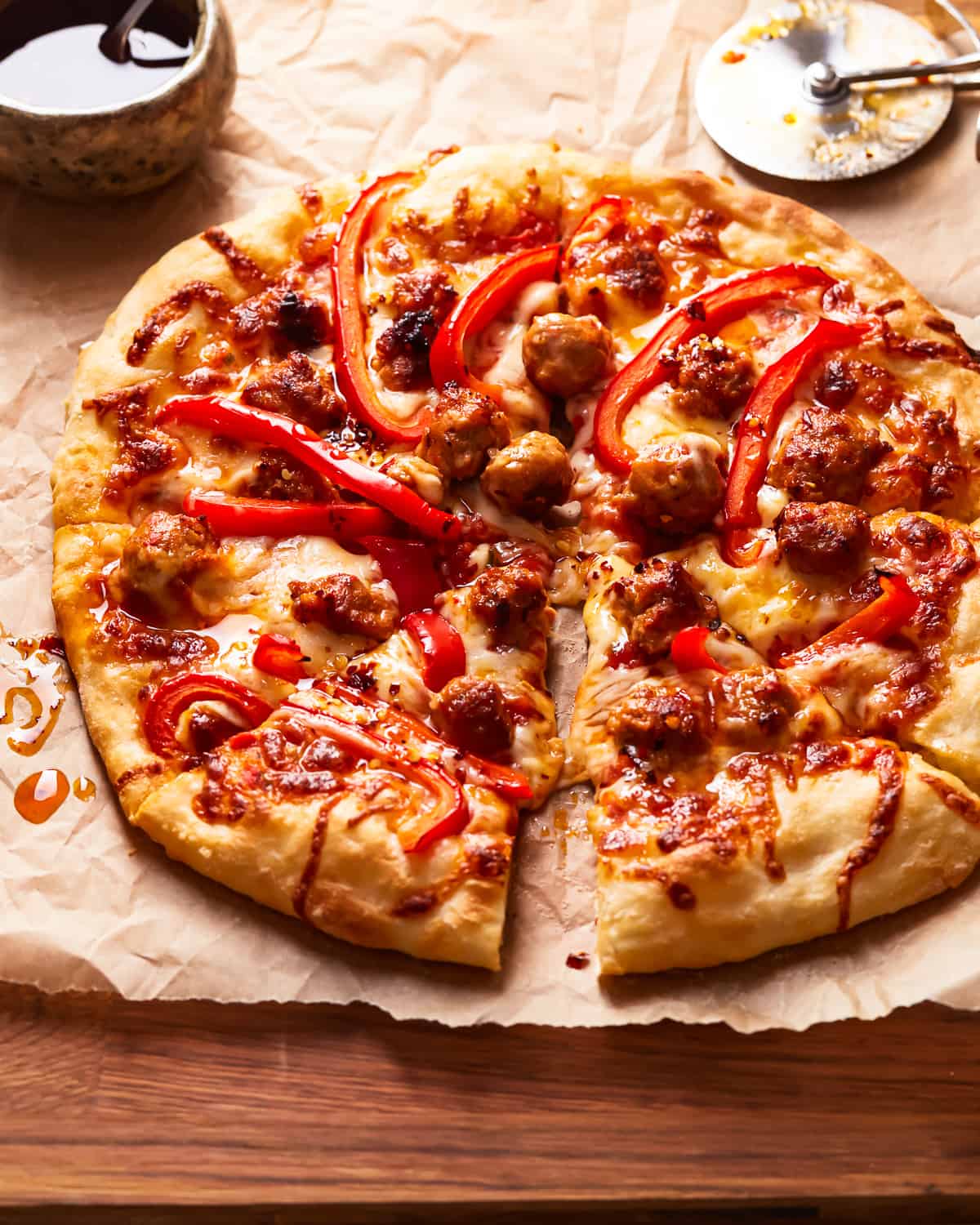 A sausage pizza on a table, cut into slices.