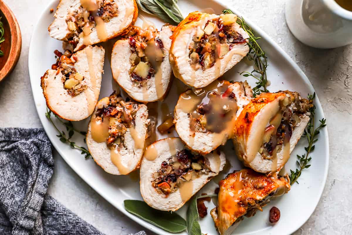 Stuffed turkey roll with cranberries and sage on a white plate.