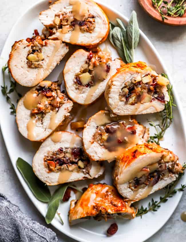 Turkey stuffed with cranberries and sage on a white plate.