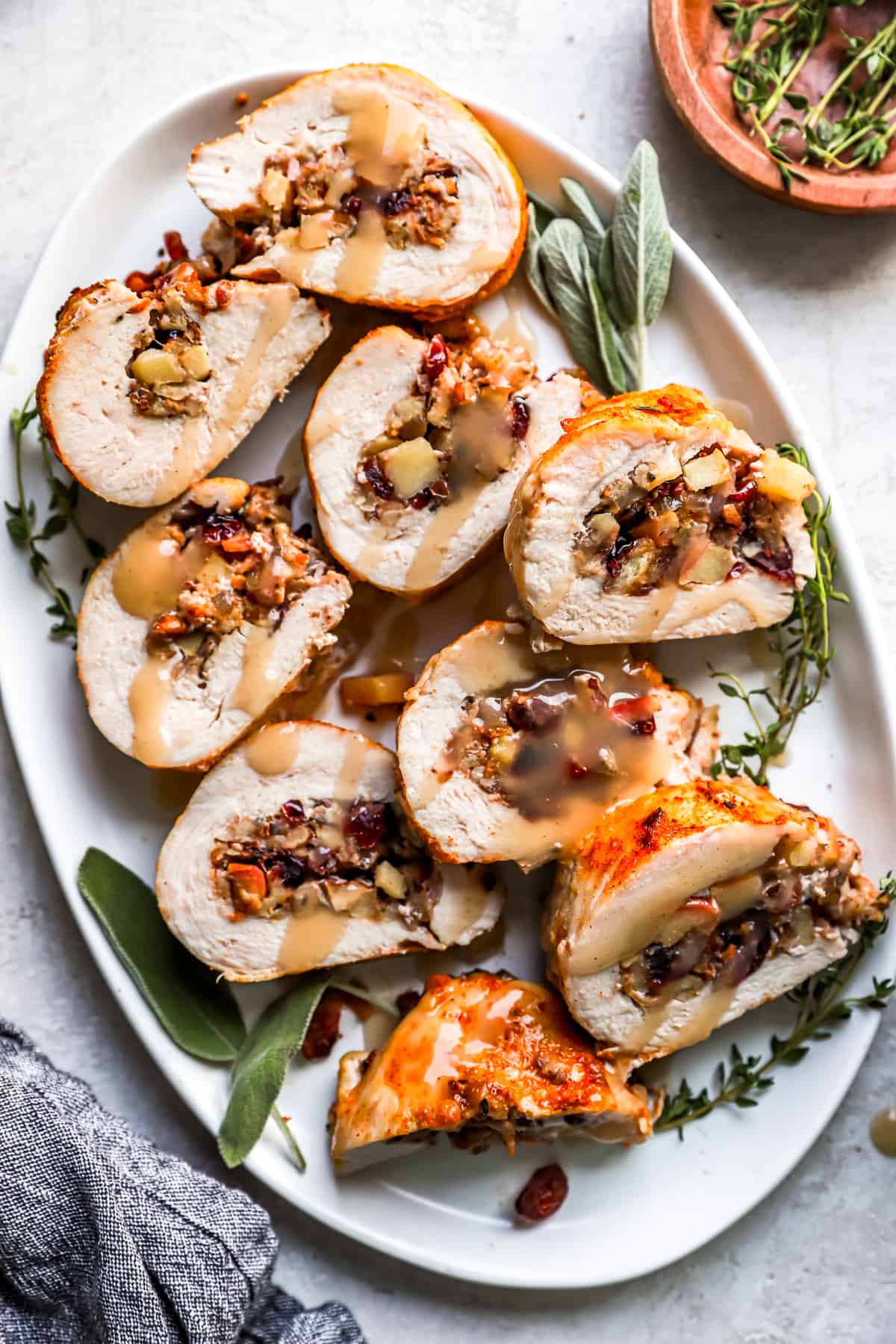Turkey roll stuffed with cranberries and sage on a white plate.