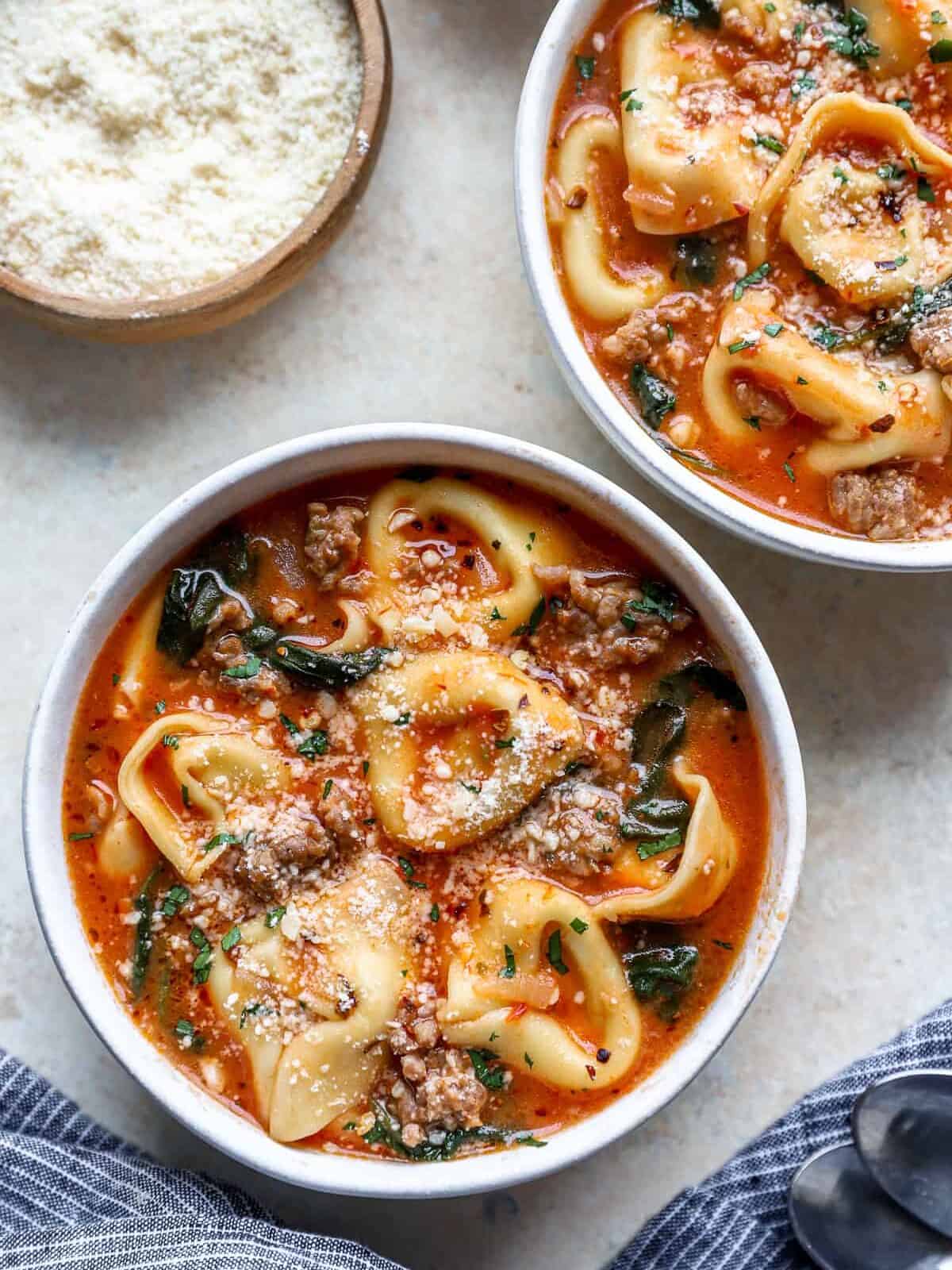 overhead view of tortellini soup in white bowls.