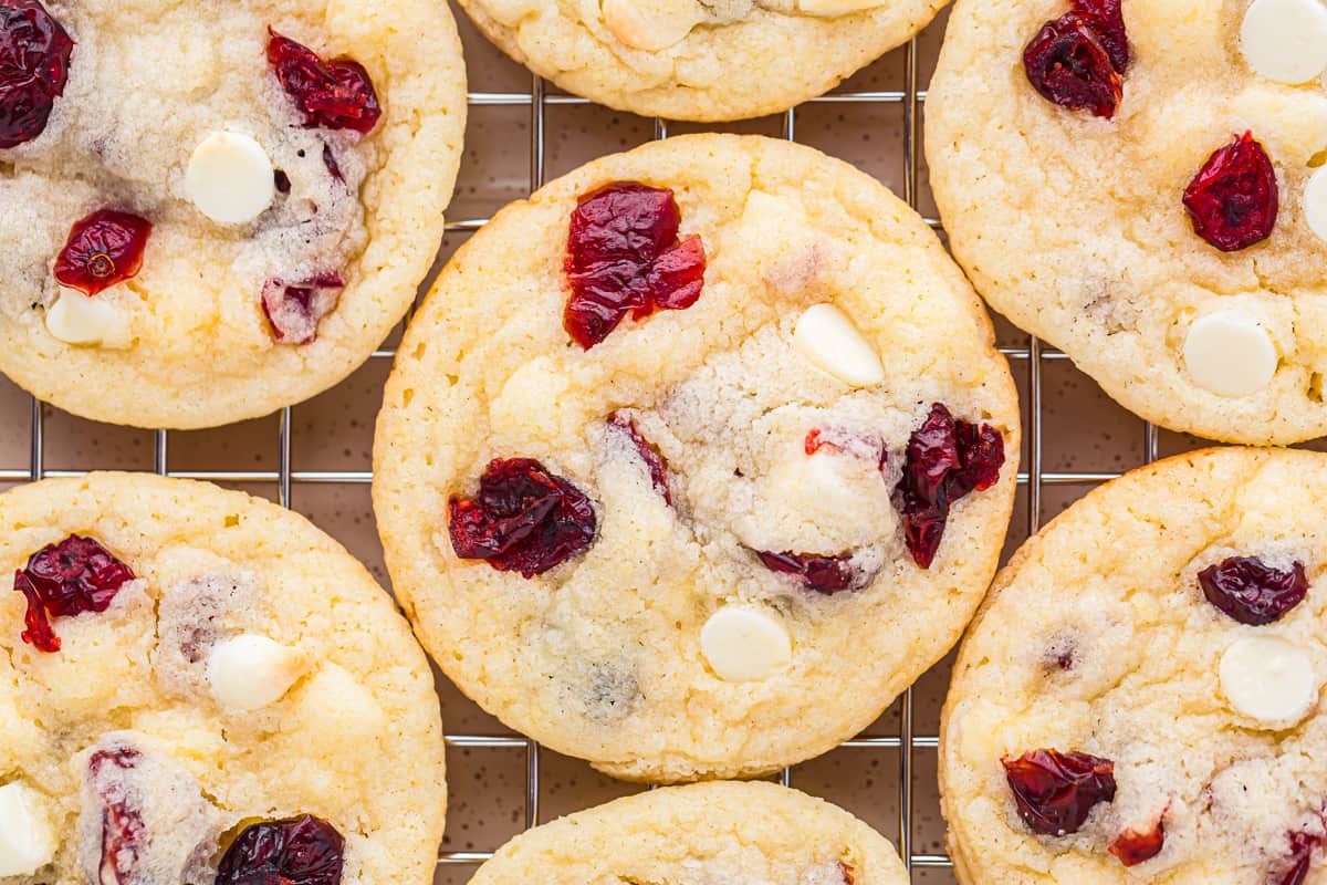 cookies studded with dried cranberries and white chocolate chips on a wire rack.