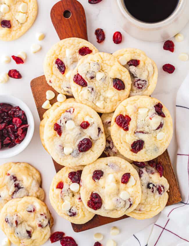 Cranberry white chocolate cookies on a cutting board with a cup of coffee.