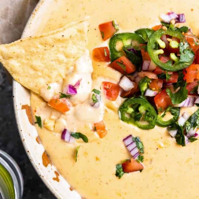 a bowl of mexican dip with chips and salsa.