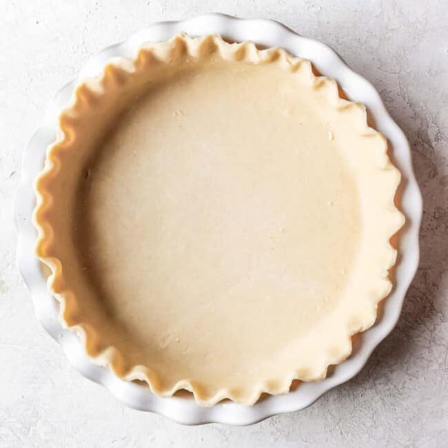 A pie crust in a white pie plate.