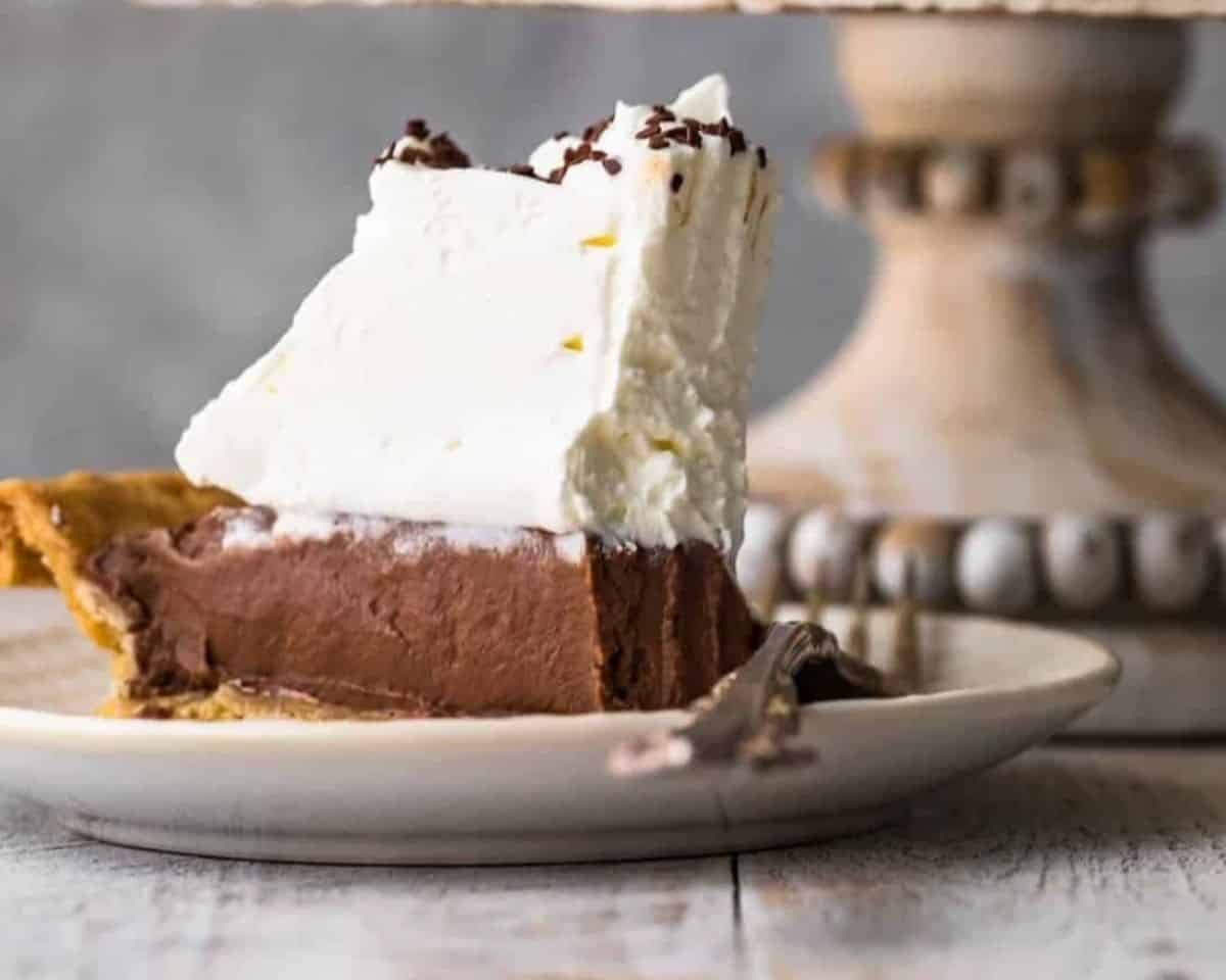 Piece of chocolate cream pie with whipped topping on a plate with a fork. - 11