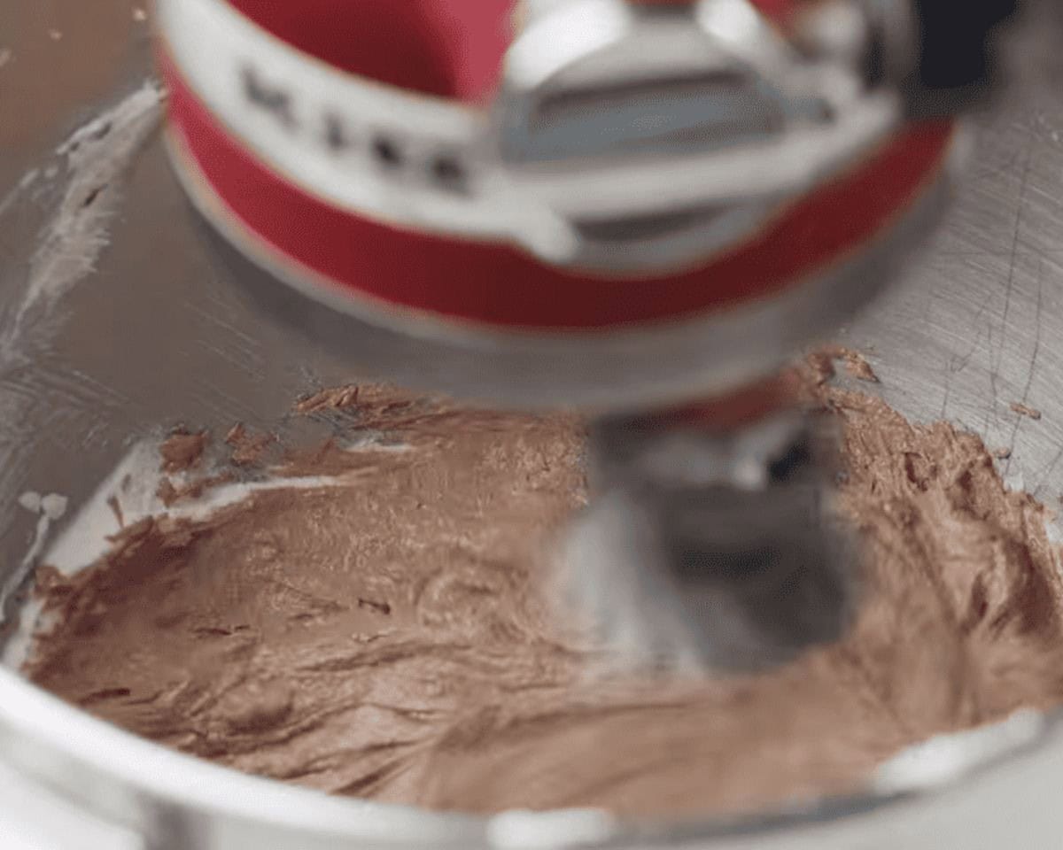 Combining the melted chocolate with the butter and sugar in a mixer. 