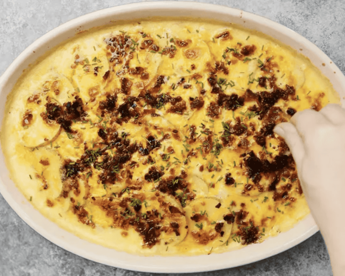 Baked potatoes casserole garnished with bacon and green onions.