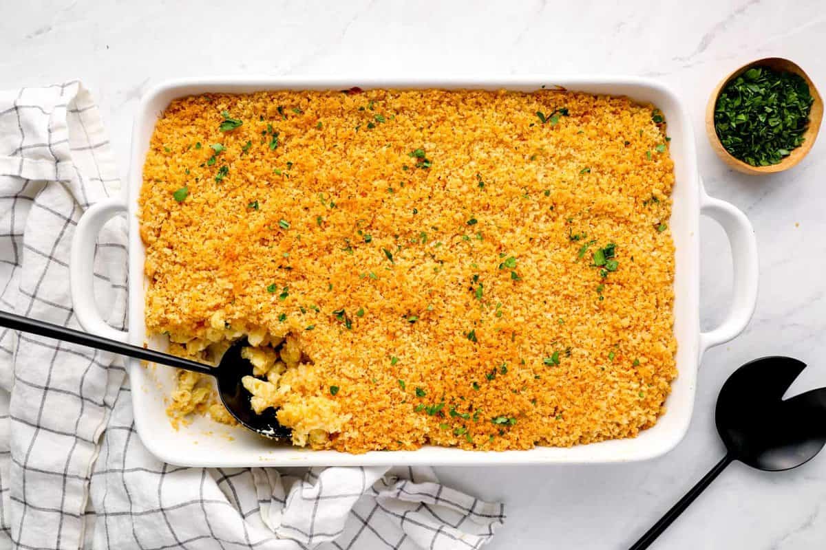overhead view of mac and cheese casserole in a white baking pan with a black serving spoon.