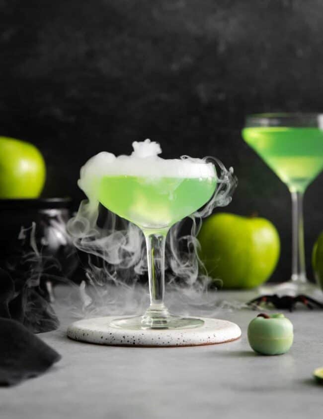 a smoking poison apple martini on a white coaster.