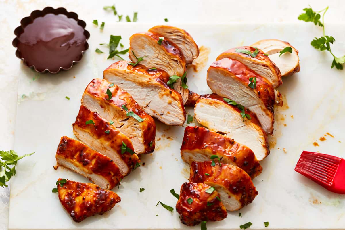 Sliced BBQ chicken on a cutting board.