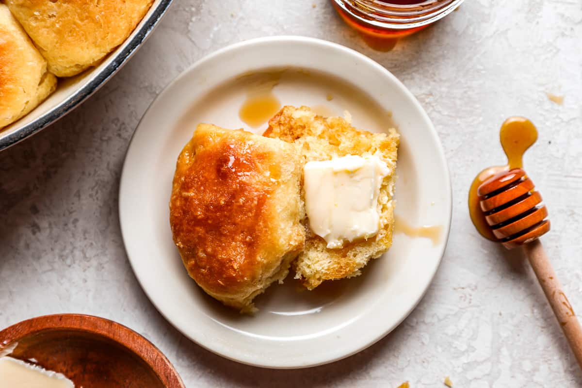 A biscuit sliced in half and topped with butter and honey.