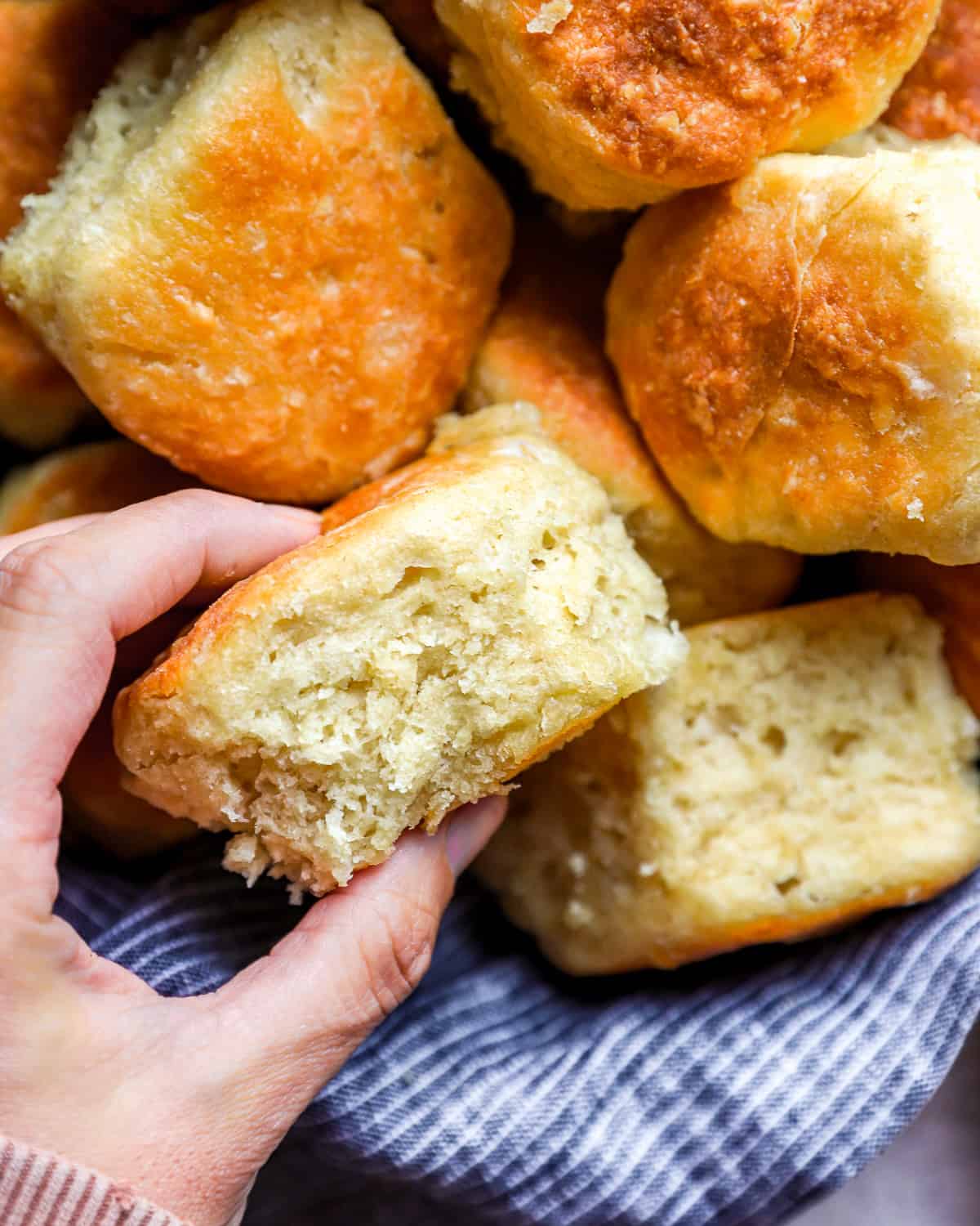 A person holding a handful of fluffy yeast biscuits.