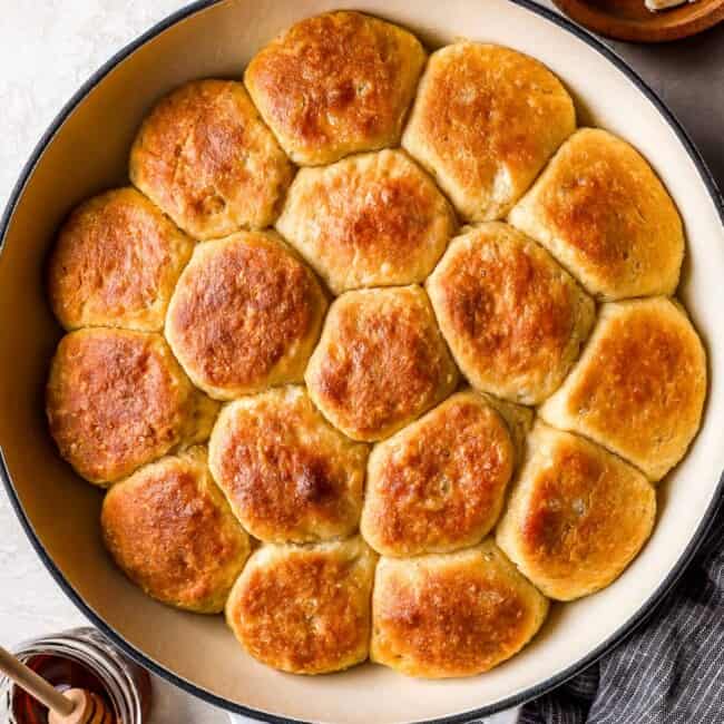 A skillet filled with biscuits and honey.