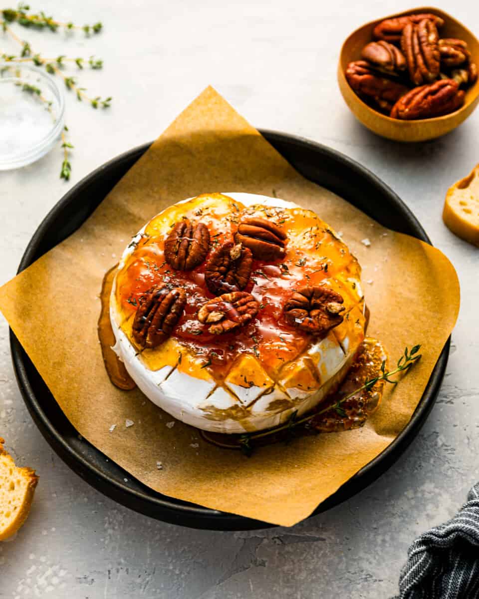 A plate of cheese with pecans and bread on it.