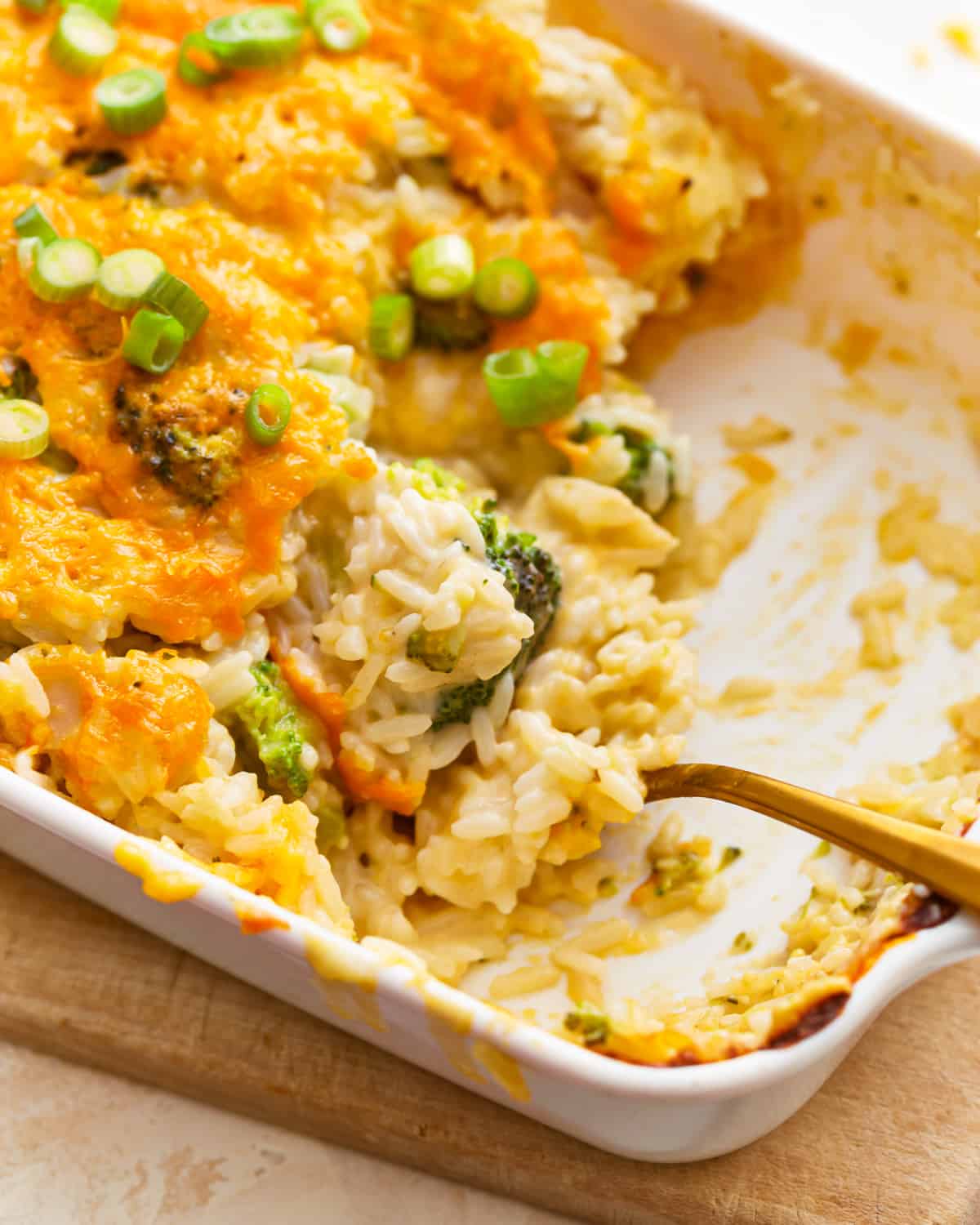 A serving spoon scooping into broccoli cheese rice casserole.