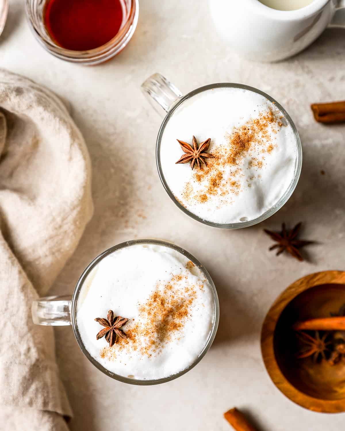 Two mugs with milk froth, cinnamon and star anise.