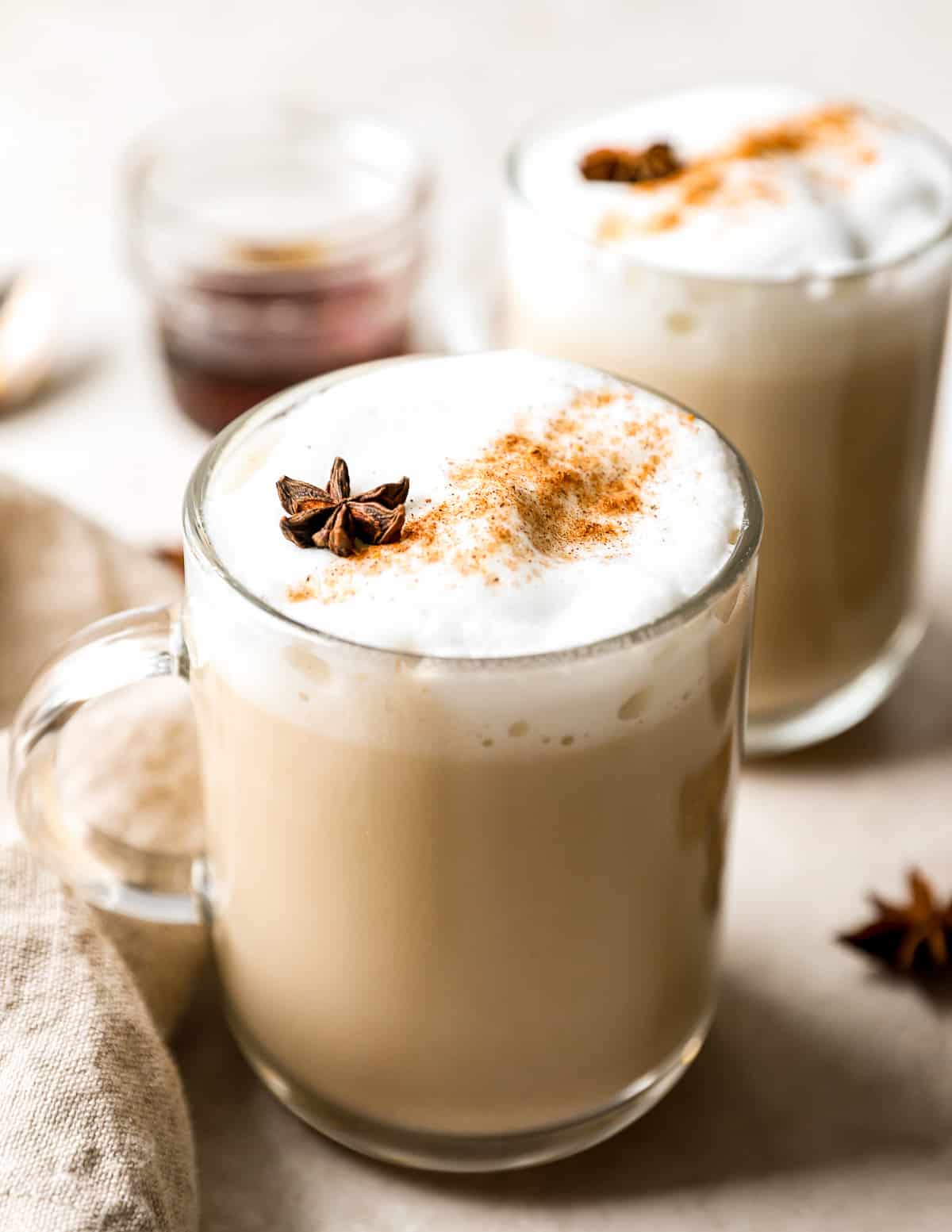 Two mugs of chai latte with cinnamon and star anise.